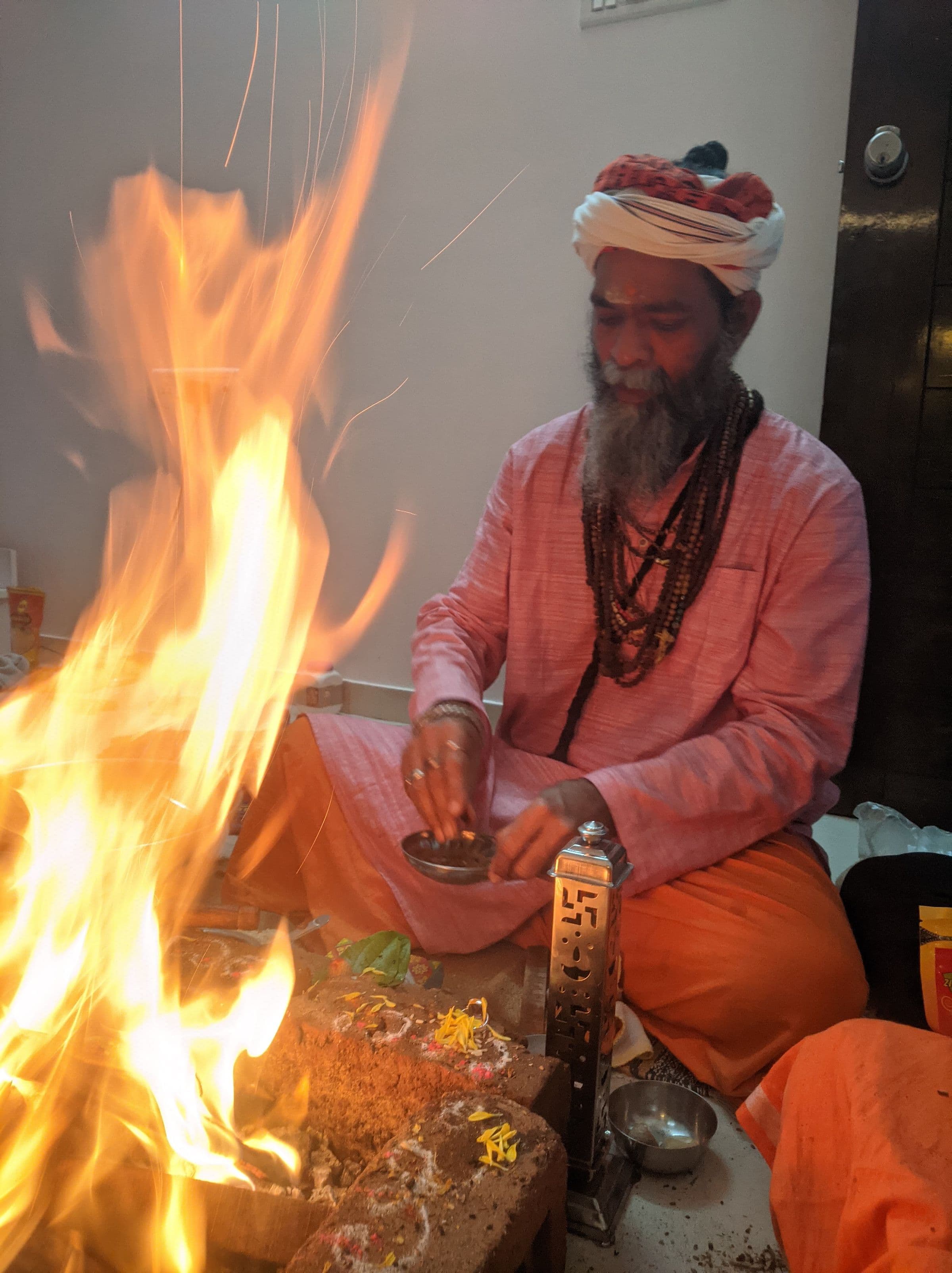 The Guru pouring an offering into the havan kund with a copper spoon